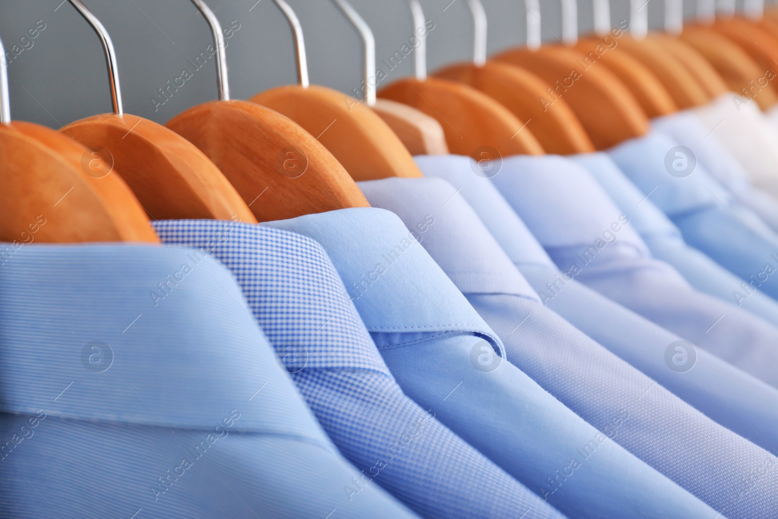 Photo of Clean clothes on hangers after dry-cleaning, closeup