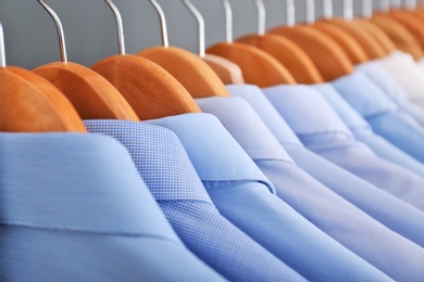 Photo of Clean clothes on hangers after dry-cleaning, closeup