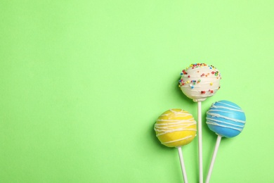 Bright delicious cake pops on color background, flat lay. Space for text