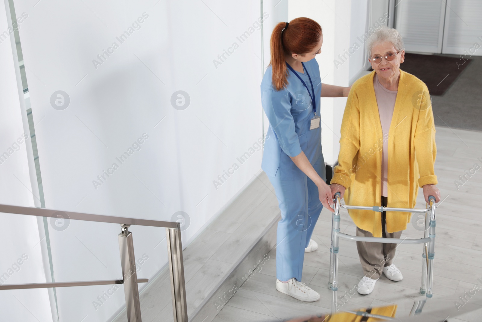 Photo of Nurse assisting senior woman with walker in hospital