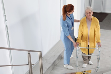 Nurse assisting senior woman with walker in hospital
