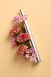 Photo of One metal bullet and beautiful flowers on yellow background, flat lay