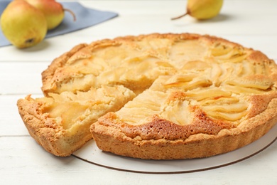 Photo of Cut delicious sweet pear tart on white wooden table, closeup