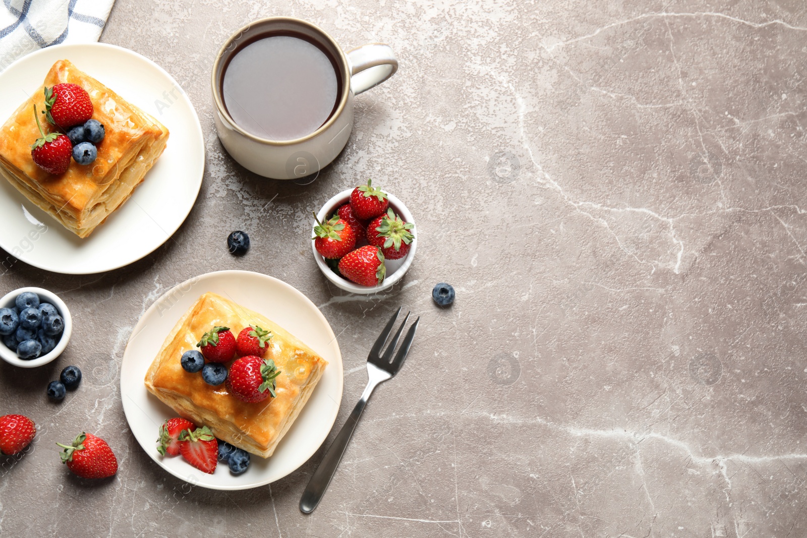 Photo of Fresh delicious puff pastry with sweet berries on grey marble table, flat lay. Space for text