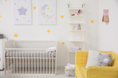 Stylish baby room interior with crib and sofa