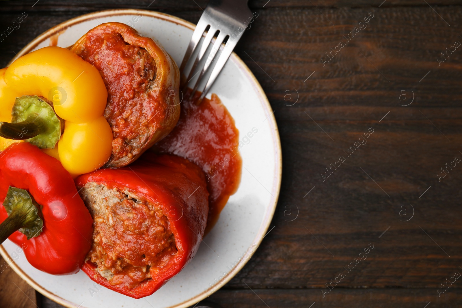 Photo of Delicious stuffed bell peppers served on wooden table, top view. Space for text