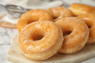 Photo of Sweet delicious glazed donuts on board, closeup