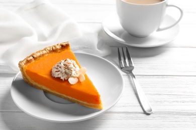 Plate with piece of fresh delicious homemade pumpkin pie on wooden table