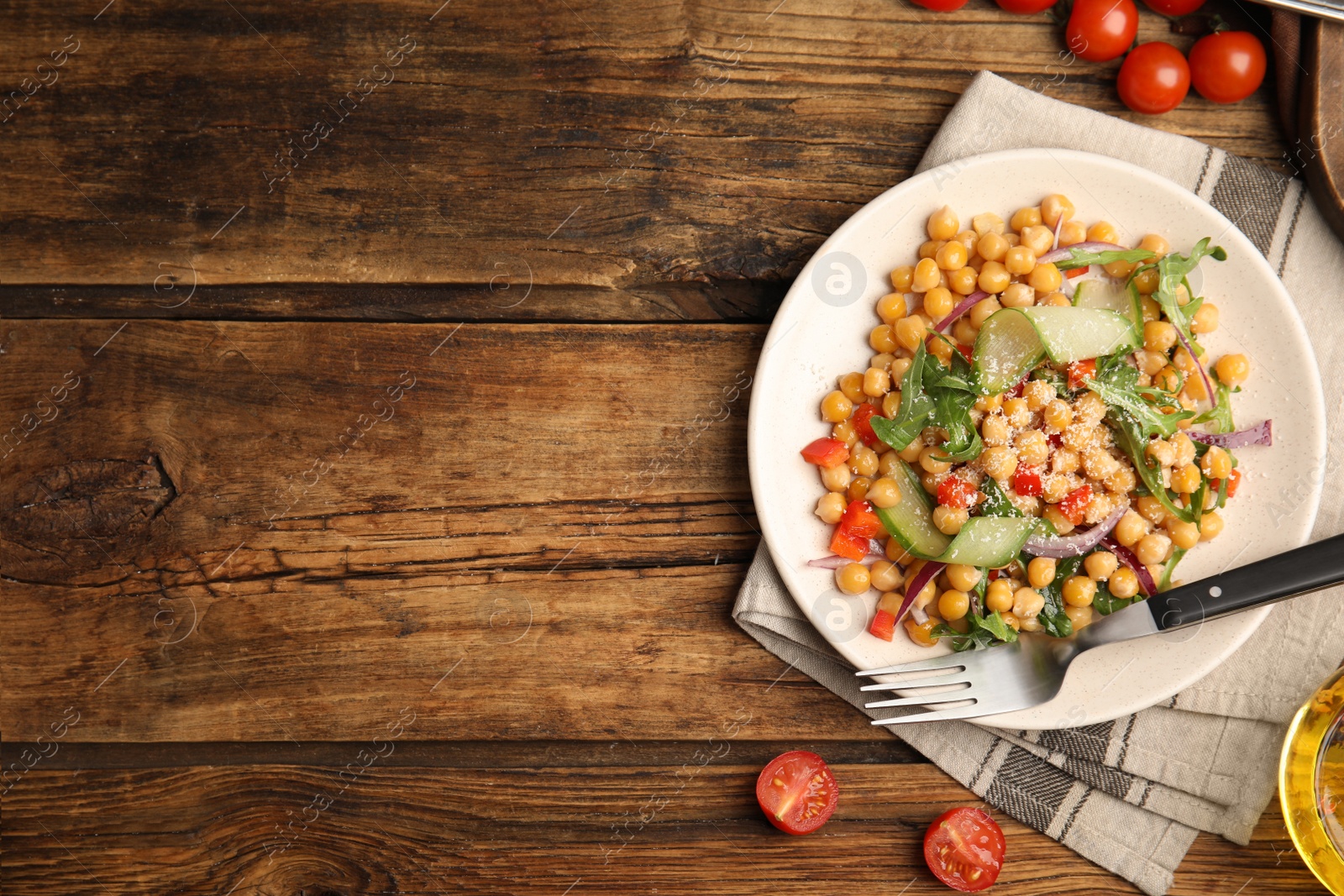 Photo of Delicious fresh chickpea salad served on wooden table, flat lay. Space for text