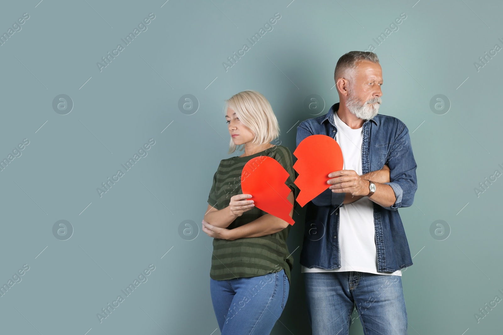 Photo of Mature couple with torn paper heart on color background. Relationship problems