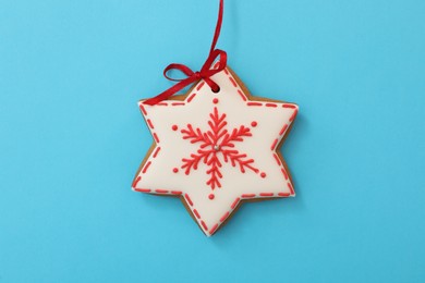 Photo of Snowflake shaped Christmas cookie on light blue background, top view