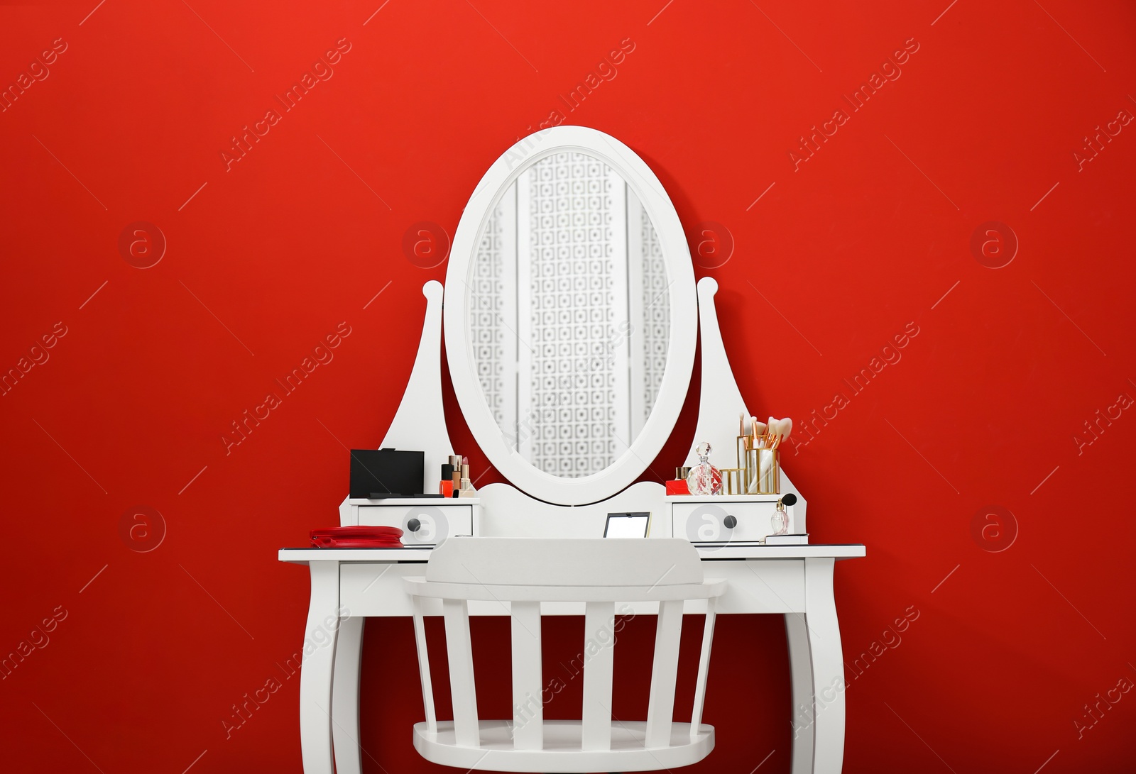 Photo of Elegant dressing table with makeup products and chair on red background