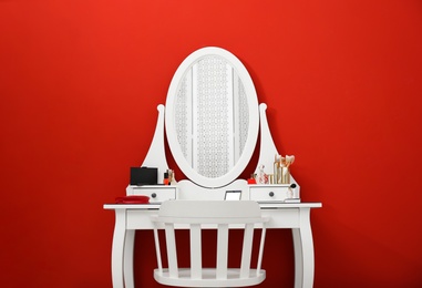 Photo of Elegant dressing table with makeup products and chair on red background