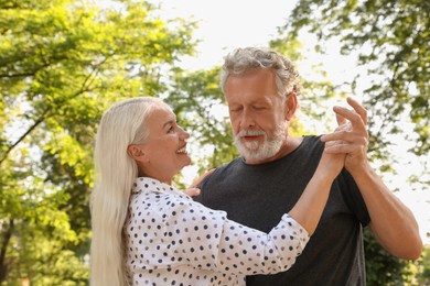 Lovely mature couple dancing together in park