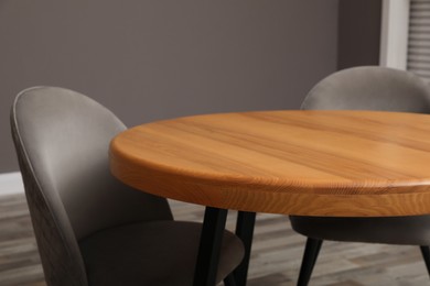 Photo of Wooden round table and grey chairs indoors, closeup