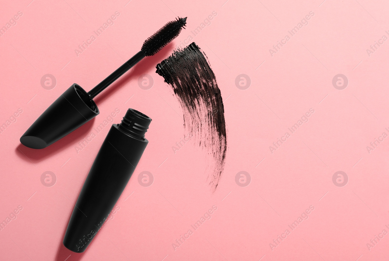 Photo of Mascara and smear on pink background, flat lay with space for text. Makeup product