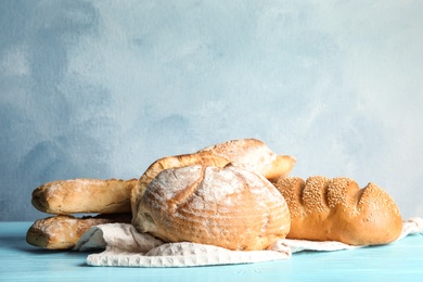 Pile of fresh bread on table against color background. Space for text