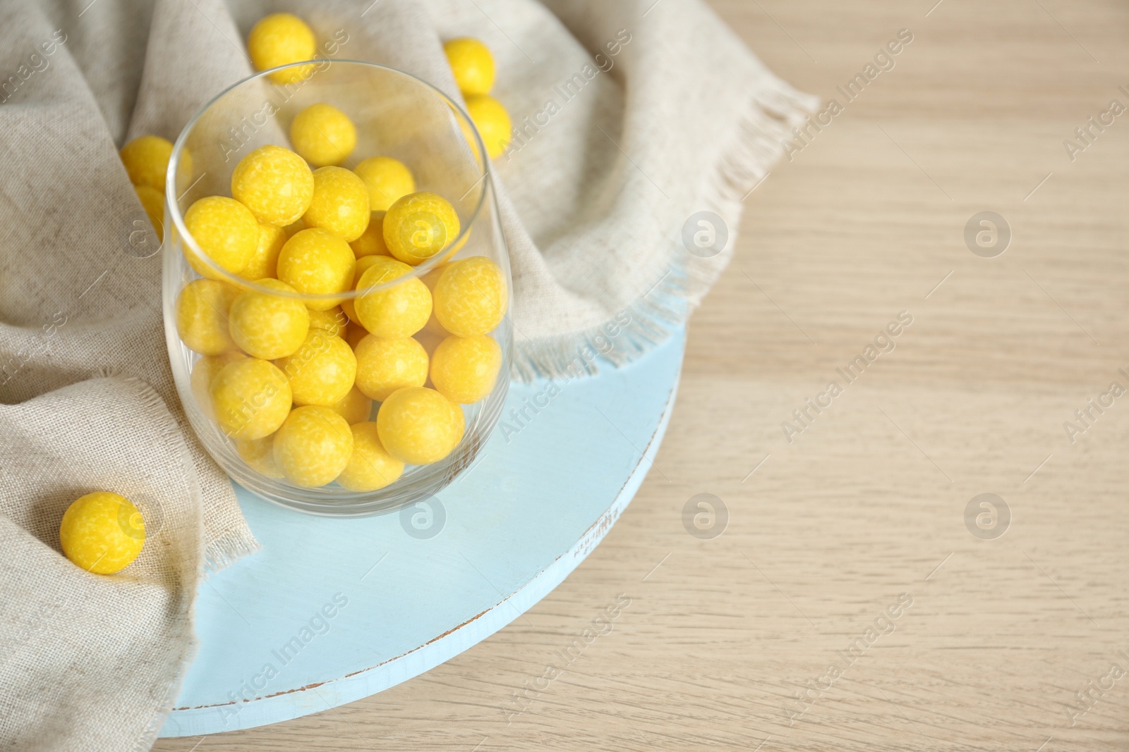 Photo of Tasty lemon drops on wooden table. Space for text