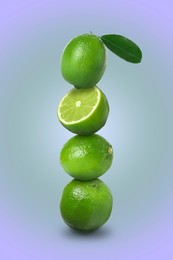 Image of Stacked whole and cut limes on violet blue background