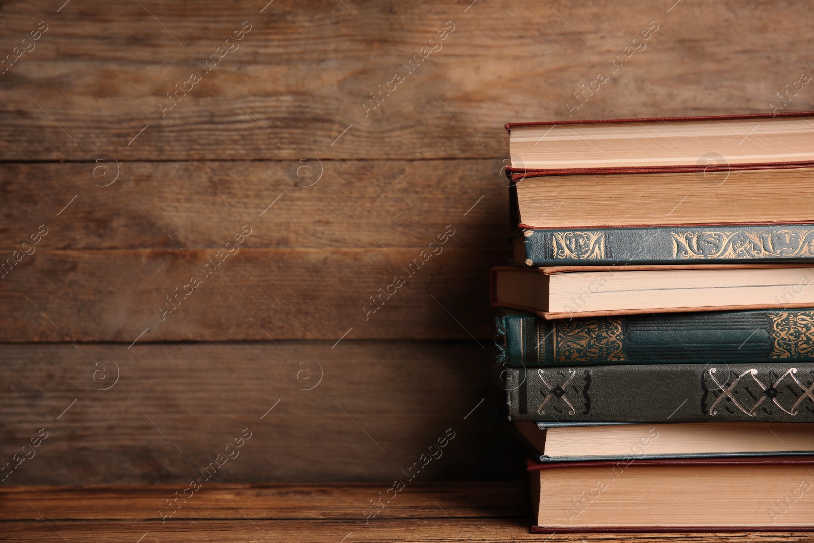 Photo of Collection of different books on table against wooden background. Space for text