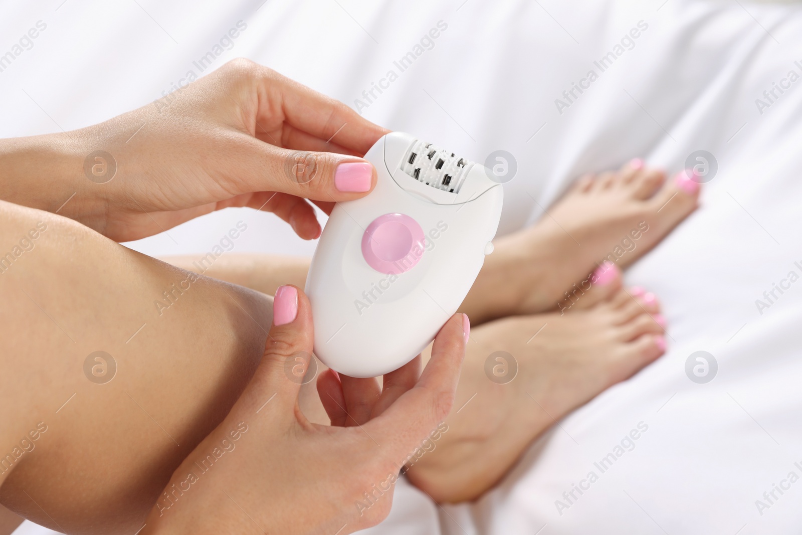 Photo of Young woman with epilator on bed, closeup