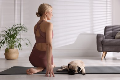 Photo of Beautiful woman with dog practicing yoga at home