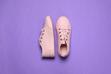 Pair of comfortable sports shoes on violet background, flat lay