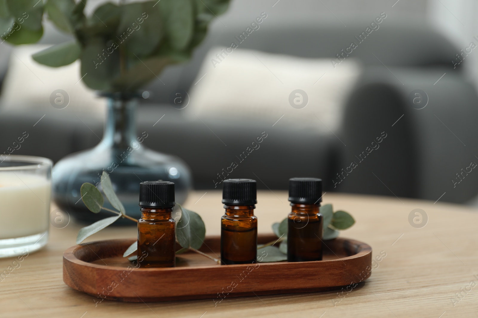 Photo of Aromatherapy. Bottles of essential oil and eucalyptus leaves on wooden table