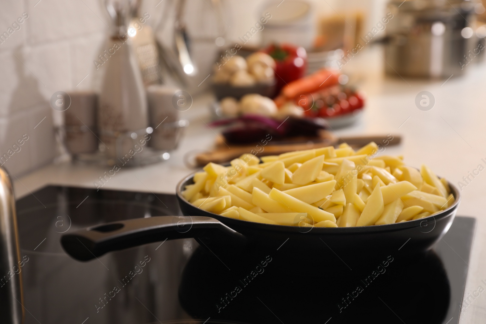 Photo of Frying pan with cut raw potatoes on cooktop