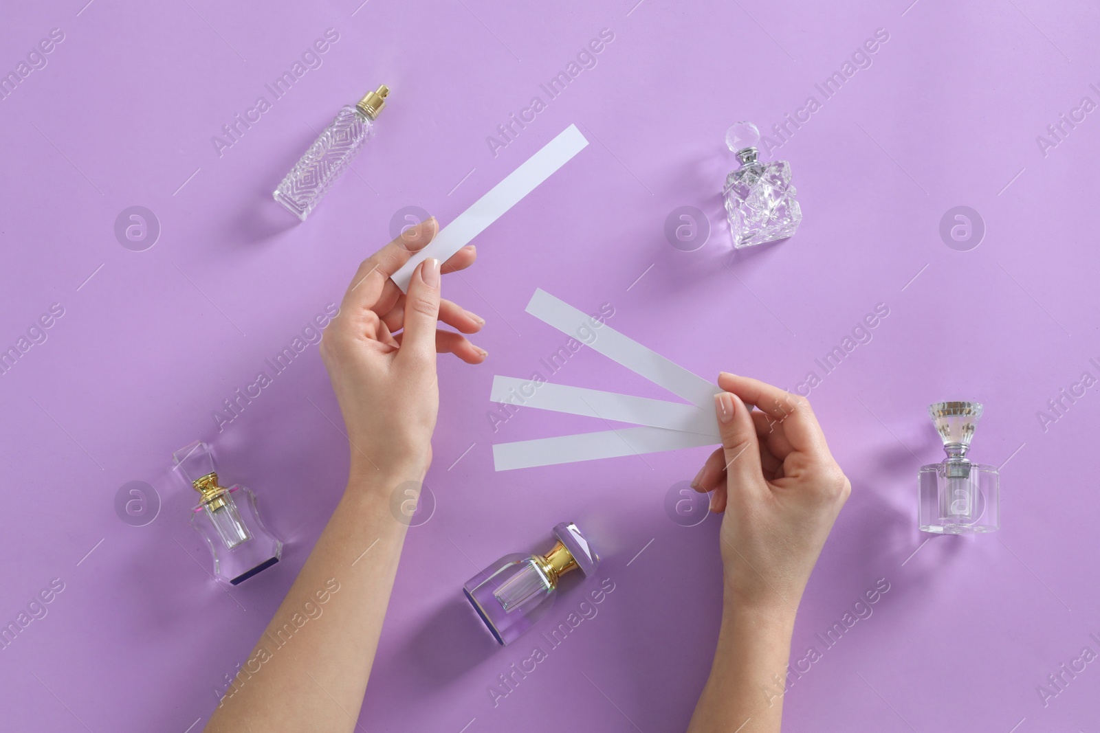 Photo of Woman with perfume blotters on violet background, top view