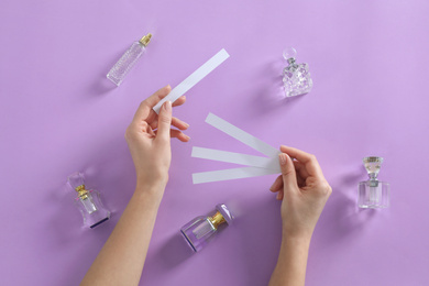 Photo of Woman with perfume blotters on violet background, top view