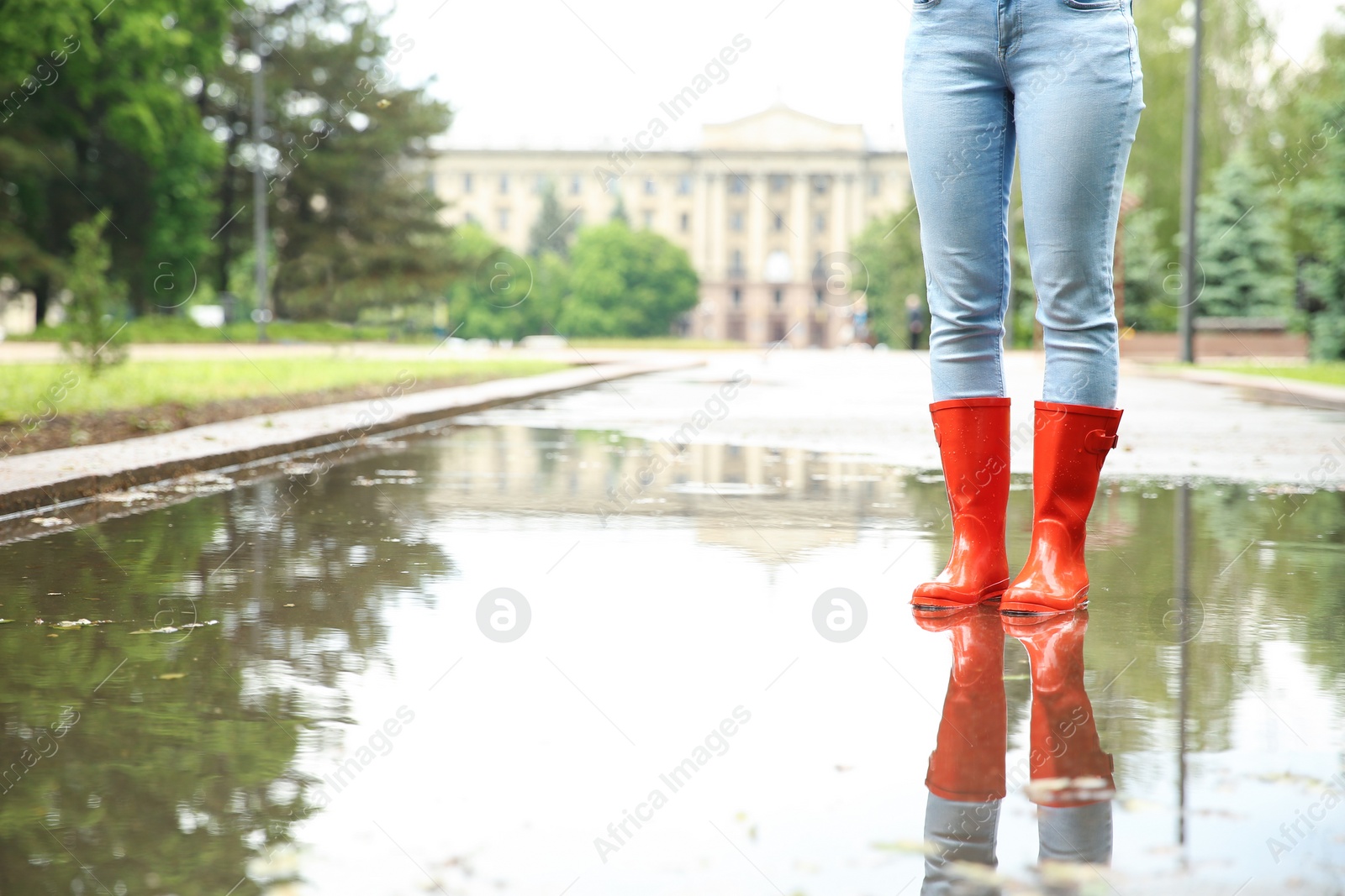 Photo of Woman with rubber boots in puddle, closeup. Rainy weather