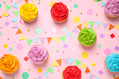 Photo of Colorful birthday cupcakes on light pink background, flat lay