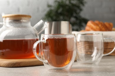 Photo of Aromatic tea in glass cup and teapot on light grey table