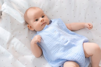 Cute little baby lying in crib at home, top view