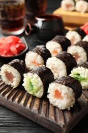Photo of Tasty sushi rolls served on black wooden table, closeup