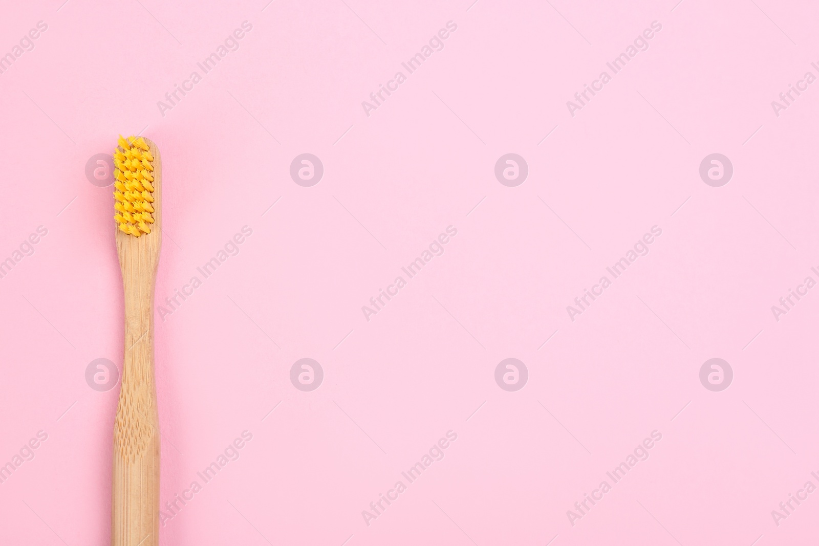 Photo of Toothbrush made of bamboo on pink background, top view. Space for text