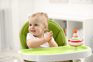 Photo of Children toys. Cute little boy with spinning top in high chair at home