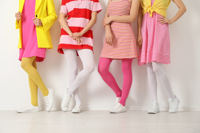 Women wearing colorful tights near white wall, closeup