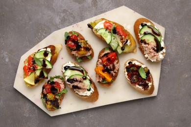 Photo of Delicious bruschettas with balsamic vinegar and different toppings on grey textured table, top view