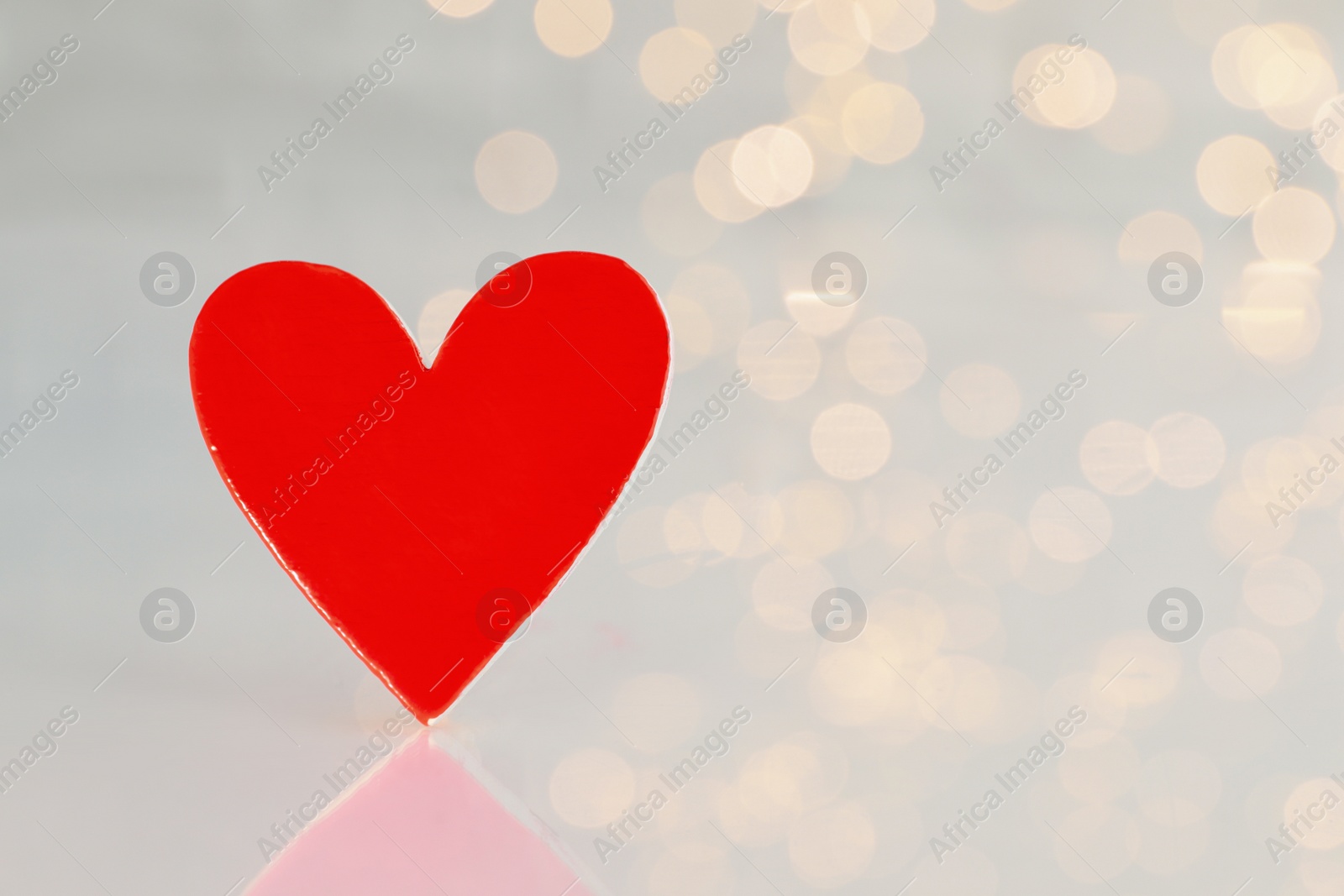 Photo of Red decorative heart against blurred lights, closeup view. Space for text