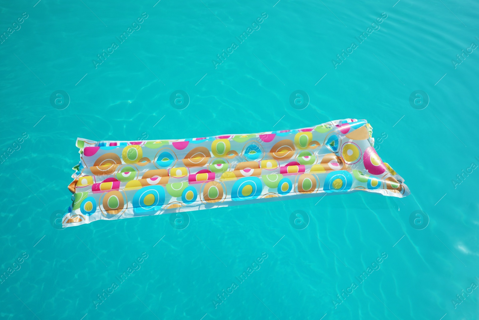 Photo of Colorful inflatable mattress floating in swimming pool on sunny day