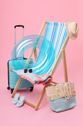 Photo of Deck chair, suitcase and beach accessories on pink background. Summer vacation