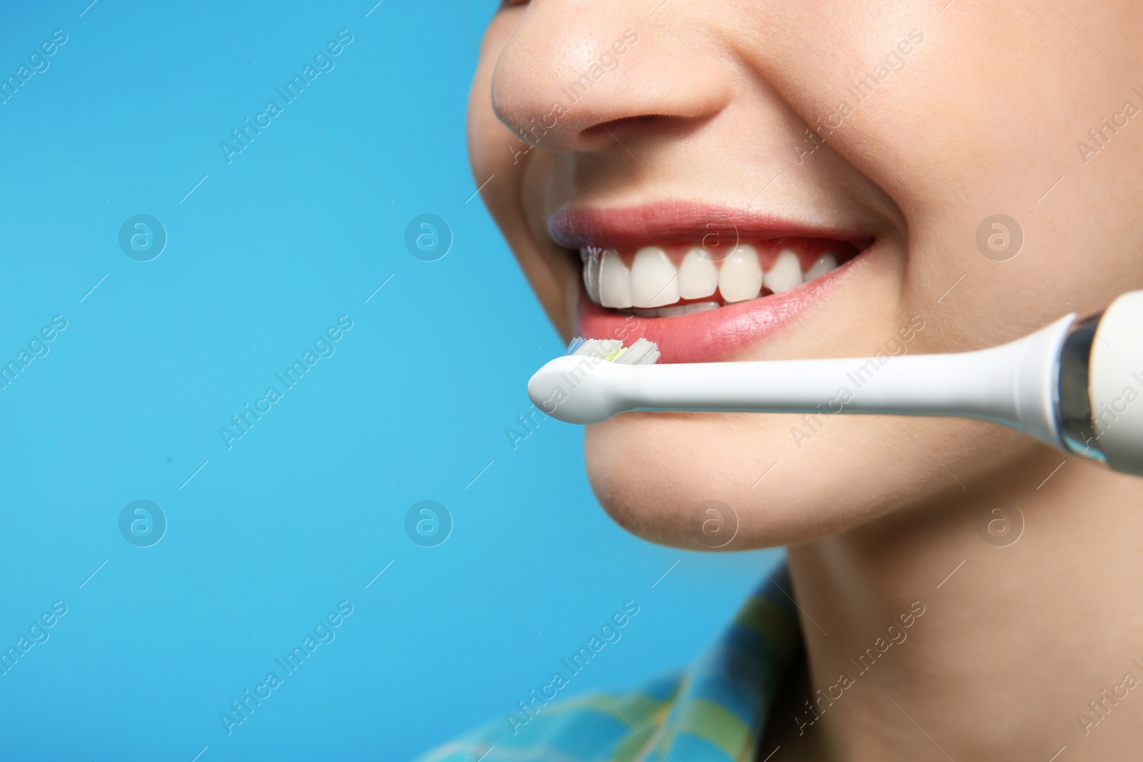 Photo of Young woman with electric toothbrush on color background, closeup. Space for text