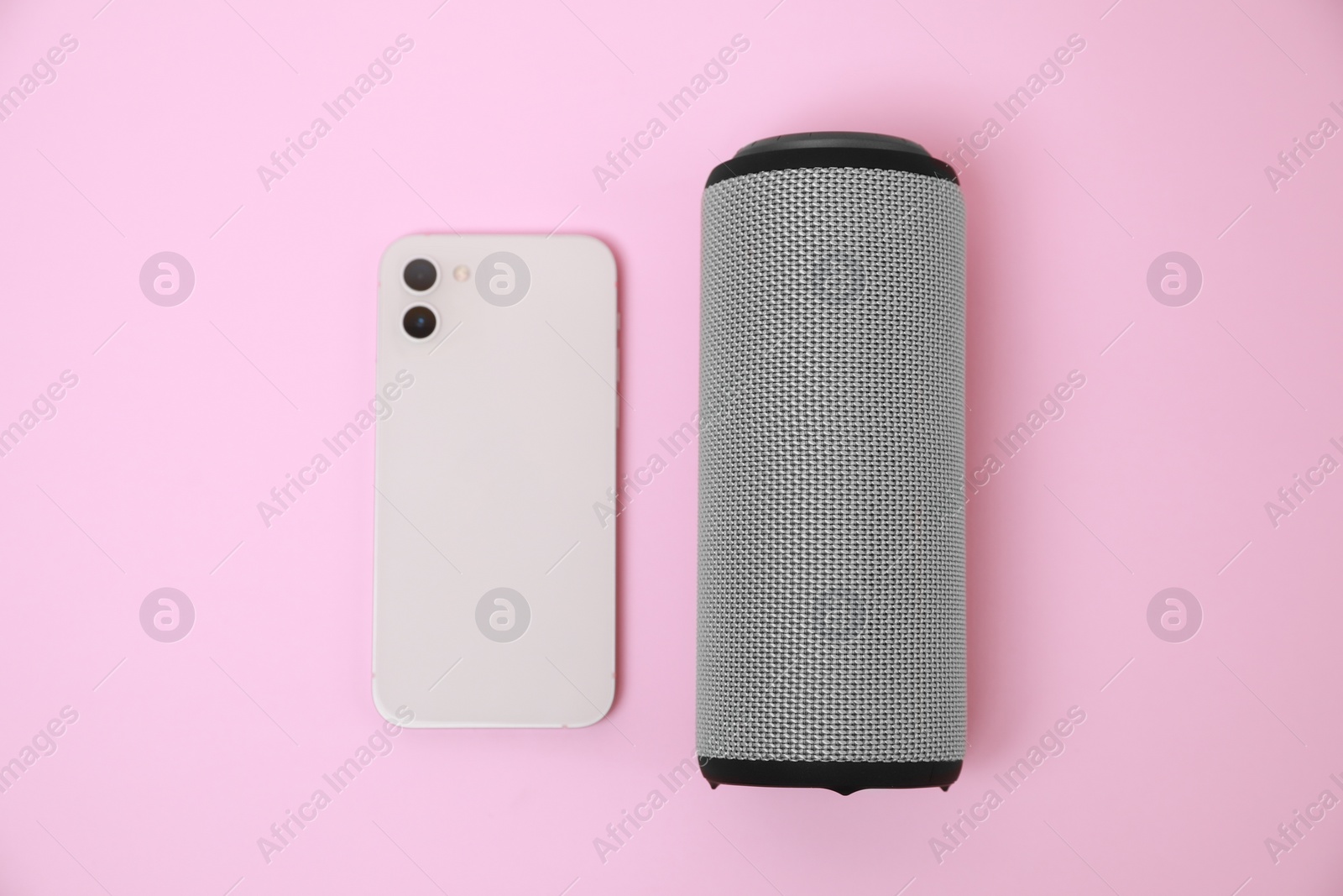 Photo of Portable bluetooth speaker and smartphone on pink background, flat lay. Audio equipment