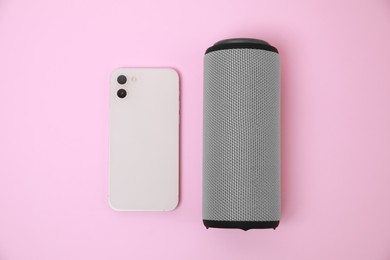 Photo of Portable bluetooth speaker and smartphone on pink background, flat lay. Audio equipment