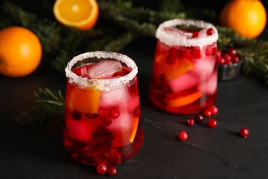 Tasty cranberry cocktail with ice cubes in glass on dark gray table, closeup