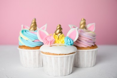 Three cute sweet unicorn cupcakes on white table