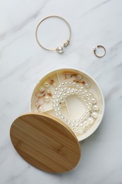 Photo of Stylish jewelry with pearls in box on white marble table, flat lay