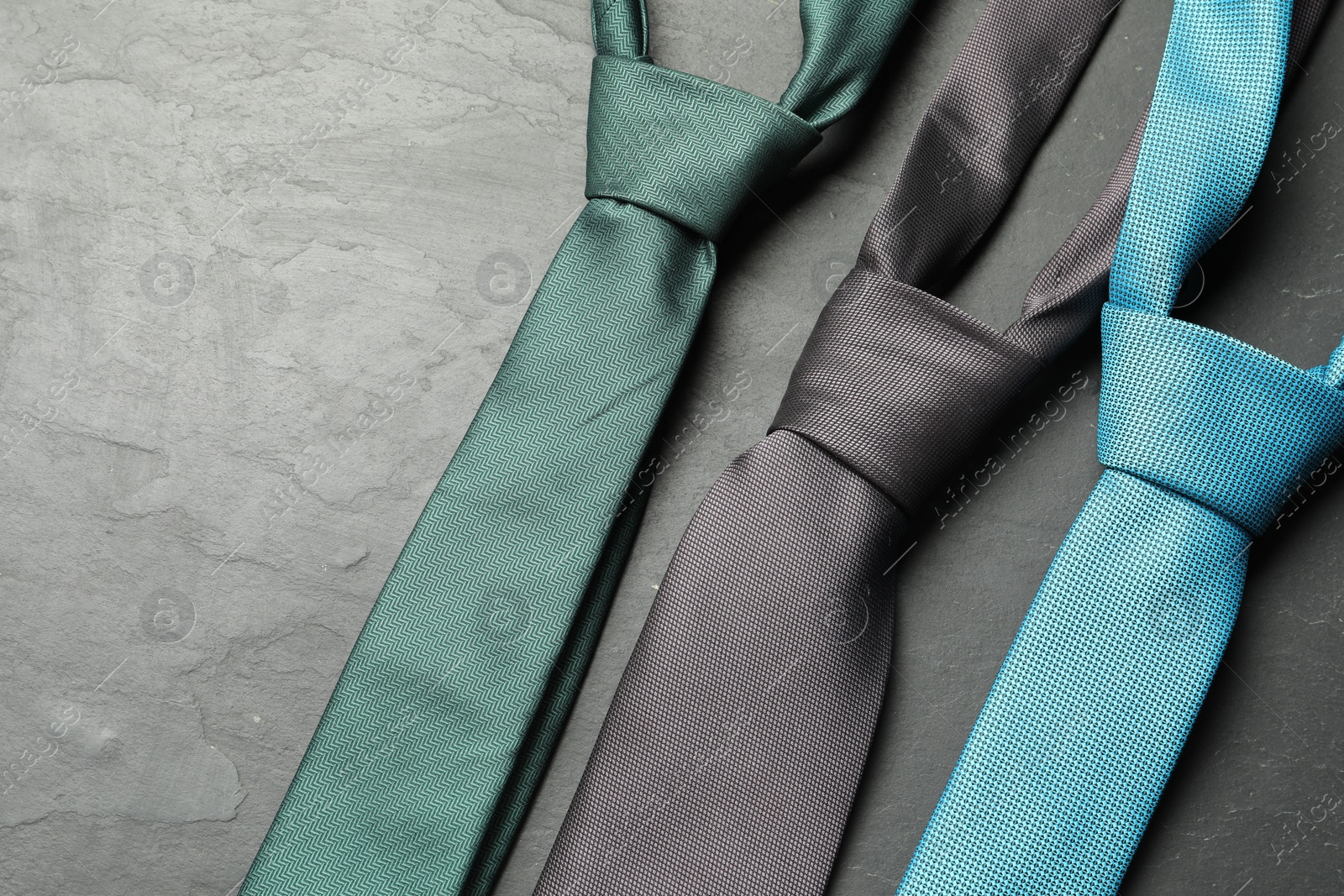 Photo of Different neckties on grey textured table, flat lay